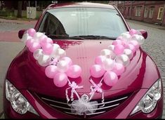 a red car with balloons tied to the hood