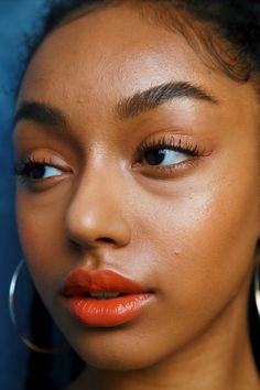 a woman with large hoop earrings on her head and orange lipstick in front of her face