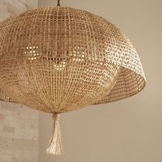 a large woven light fixture hanging from a ceiling in a room with stone wall and white brick walls