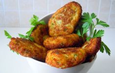 some fried food in a white bowl on a counter top with parsley and parsley