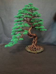 a bonsai tree with green leaves is shown on a black surface and gray background