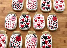 twelve decorated cookies with hearts in mason jars on a wooden table, ready to be eaten