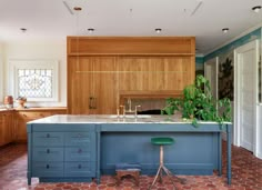 a kitchen with blue cabinets and an island in the middle of it, surrounded by red tile flooring