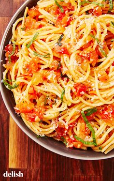 a bowl filled with pasta and sauce on top of a wooden table