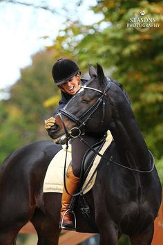 a woman riding on the back of a black horse