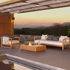 an outdoor patio with wood furniture and fire pit on the deck overlooking mountains at sunset