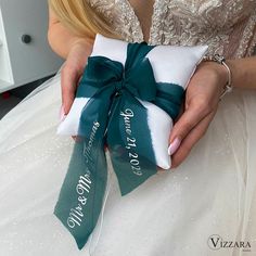 a woman in a wedding dress holding a white and green bow