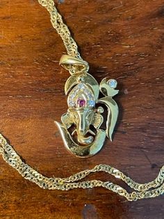 Beautiful and Intriquing 18K Yellow Gold Ruby and Diamond Om Ganesh Pendant Necklace is a rare opportunity to add to someone's jewelry collection.  Om Ganesh, the elephant headed Hindu God of prosperity and wisdom, is magnificently portrayed in this creation.  The pendant weighs 2.1 grams displaying a ruby (1.3mm) and eight diamonds (four 1mm and four 1.3mm).  The pendant is not marked, but tests for 18k gold.  The sparkling 18K Yellow Gold 17 inch twisted chain necklace is hallmarked 750 (18k) Spiritual 22k Gold Necklace With Gemstone, Yellow Gold Temple Necklace With Gemstone For Gifts, Ceremonial Gold Diamond Necklace, Diamond Temple Necklace As Gift, Spiritual Yellow Gold Temple Necklace Hallmarked, Spiritual Formal Jewelry For Festivals, Spiritual Jewelry For Formal Festivals, Traditional Polished Wedding Necklace, Gold Diamond Temple Necklace For Gift