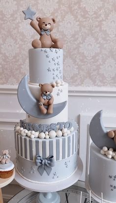 a three tiered cake with teddy bears on top and moon in the middle, surrounded by cupcakes