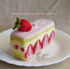 a piece of cake on a plate with a strawberry on top and green leafy decoration