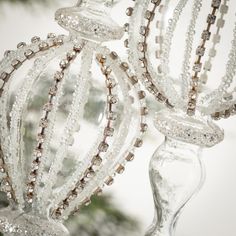 two glass candlesticks with beaded decorations hanging from the top and bottom of them