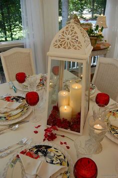 a table set with plates, candles and napkins