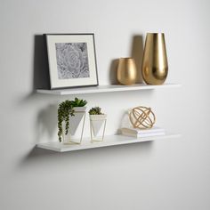 two white shelves with gold vases and plants on them