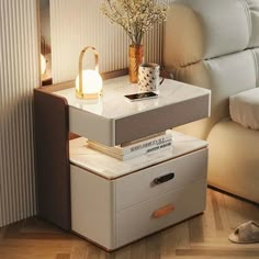 a white table with two drawers and a lamp on the top, next to a couch