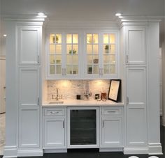 a kitchen with white cabinets and marble counter tops