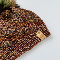 a multicolored hat with a green pom - pom on top of it