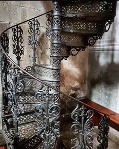 an ornate metal spiral staircase next to a brick wall