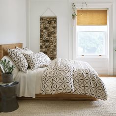 a bed with white sheets and pillows in a bedroom next to a large wooden headboard