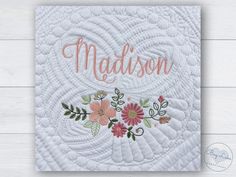 a white quilt with pink flowers and the word madison in cursive font on it