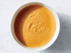 a white bowl filled with brown liquid on top of a table