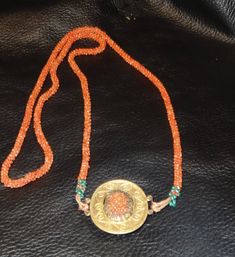 A very beautiful and hard to find hand woven genuine coral bead necklace originating in China and dating from about 1880-1900. A central gilded metal medallion features handwoven coral beads and is the same on both sides of the medallion. There is no clasp. The length is approximately 32 inches long. The medallion measures 1.25 by 1.50 inches. These long Chinese necklaces became the rage in the West during the 1920s. This one is a rare find and a beauty! *Fine jewelry authenticated by a GIA Gemo Traditional Medallion Necklace With Coin Pendant, Traditional Handmade Round Medallion Necklace, Ceremonial Handmade Medallion Necklace, Traditional Beaded Medallion Jewelry, Traditional Coin Medallion Necklace, Antique Handmade Orange Necklaces, Traditional Orange Round Necklace, Orange Handmade Jewelry For Ceremonial Use, Handmade Orange Jewelry For Ceremonial Occasions