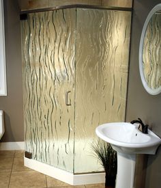 a bathroom with a glass shower door and sink in it's corner, next to a mirror on the wall