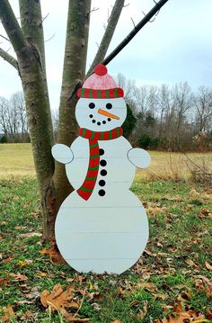 a wooden snowman standing next to a tree