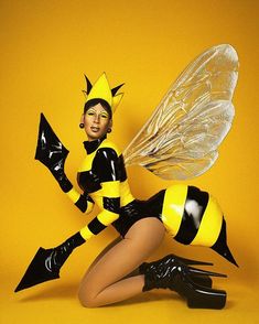 a woman dressed in black and yellow is posing with a bee on her leg,