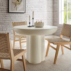 a white table and chairs in a room with brick wall behind it, along with a painting on the wall