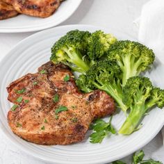 two white plates topped with meat and broccoli