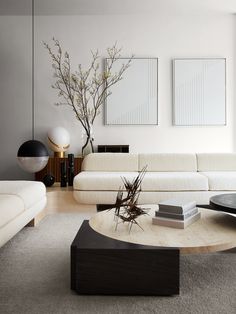 a modern living room with white furniture and art on the wall behind the coffee table