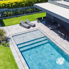 an aerial view of a swimming pool with lounge chairs on the side and grass around it