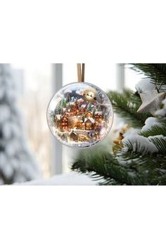 a snow globe ornament hanging from a christmas tree in front of a window