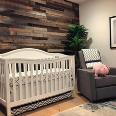 a baby's room with a white crib and wooden wall behind the crib