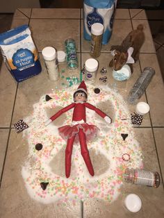 an elf is sitting on the floor in front of some bottles and other items that have been placed around it