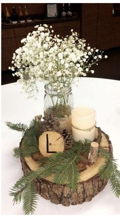 a vase with flowers and candles sitting on a wooden slice in the middle of a table