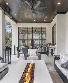 an outdoor living room with fireplace and seating on the outside patio, surrounded by wood plank ceilinging