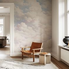 a chair and ottoman in front of a wall with clouds painted on it