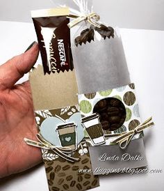 a hand is holding an open bag of coffee beans and chocolate bars with tags attached to them