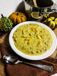 there is a bowl of soup on the table next to some pumpkins and gourmet items