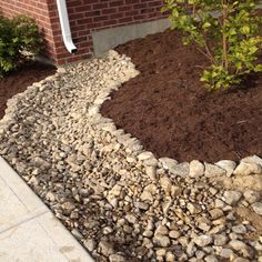 a rock garden bed in front of a brick house