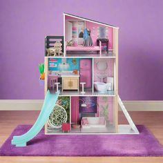 a doll house with a slide in front of it on a purple carpeted floor