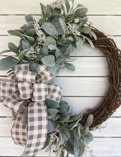 a wreath that is hanging on the side of a wall with eucalyptus leaves and white flowers