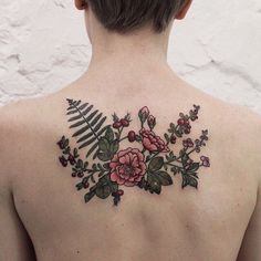 the back of a woman's shoulder with flowers and fern leaves on it