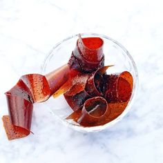 a glass bowl filled with sliced up carrots on top of a white countertop