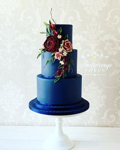 a three tiered blue cake with flowers on top