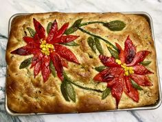 a loaf of bread decorated with poinsettis and leaves on a marble surface