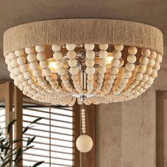 a chandelier made out of wood balls and rope hanging from the ceiling in a living room