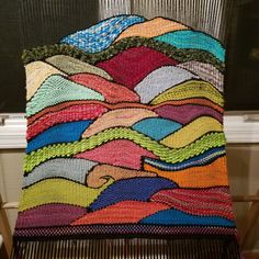 a multicolored crocheted blanket sitting on top of a chair