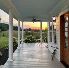 a bicycle is parked on the front porch of a house with columns and pillars that are painted white